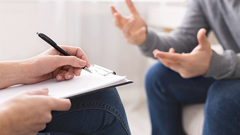 Psychotherapist writing notes, giving diagnosis to emotional man patient