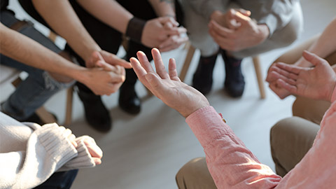 Close-up of therapist's hands explaining a problem to his patients