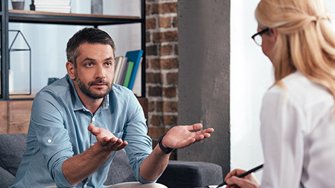 mature man with wide arms talking to female psychiatrist at her office