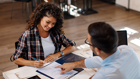 Young woman signing contract with manager