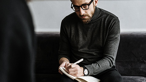 Male therapist taking notes on client's details