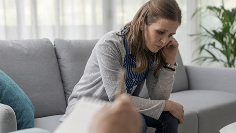 Depressed woman sitting on the therapist couch, mental health concept