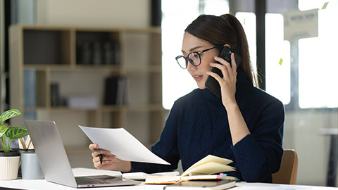 Businesswoman smile got good news on smartphone while working on computer