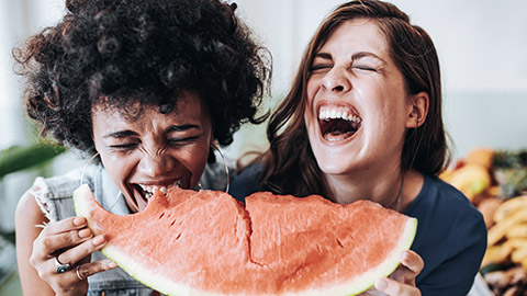 Friends eating watermelon while laughing