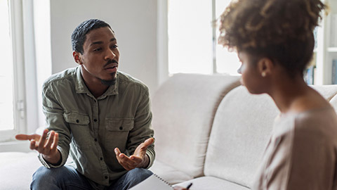 Unhappy anxious depressed young black man attending therapy session with psychologist