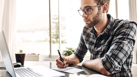 Man taking notes with computer