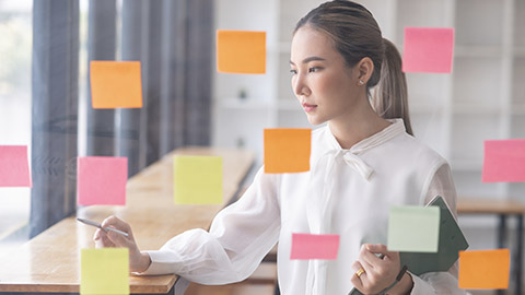 Young Asian businesswoman holding a note on the board presenting about financial business