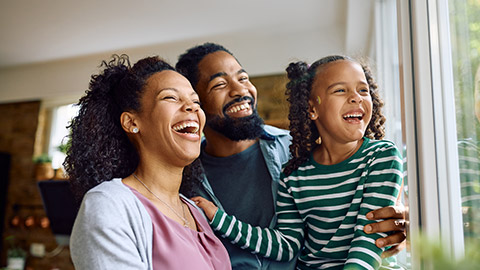 parents and their daughter having fun and laughing while looking out of a window at home