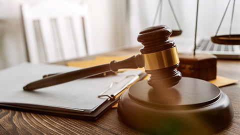 Justice and law concept.Male judge in a courtroom with the gavel, working with, computer and docking keyboard, eyeglasses, on table in morning light