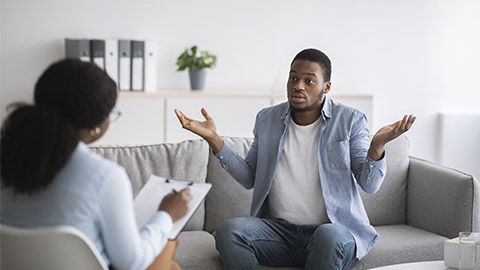 Puzzled young black guy having session with psychologist