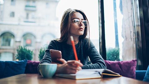 thoughtful woman looking outside while planning