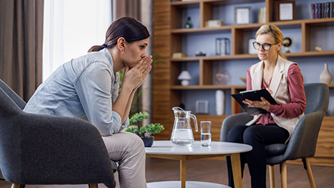 Upset young woman has counseling session with female psychologist in the office