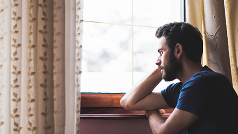 a man sitting by the window in deep sadness