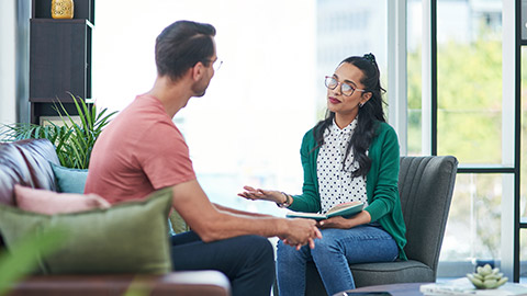 therapy or counseling with a woman psychologist and male patient talking in her office