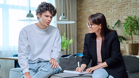 Young male communicates with female psychologist at therapy session in office