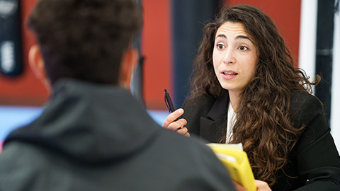 Female sports psychologist with pen and folder speaking with young man