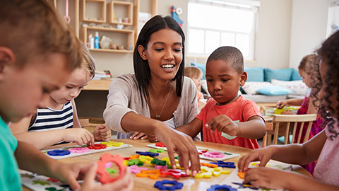 Teacher And Pupils Using Flower Shapes In Montessori School