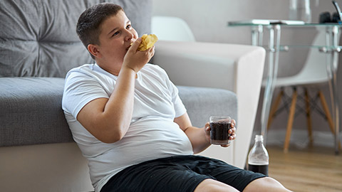 fat overweight teenager boy has bad nutrition, eat unhealthy food