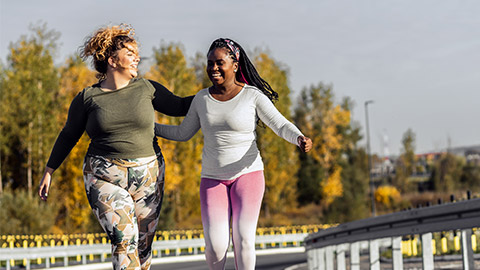 Two young plus size women jogging together on road.