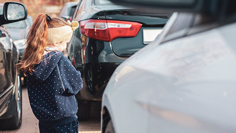 A child standing unsupervised among several vehicles