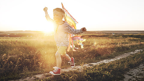 A child running outdoors with a colorful kite