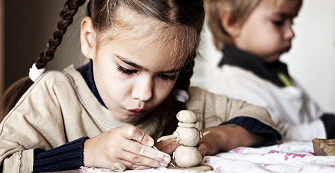 A child making a sculpture while making a serious and focused face