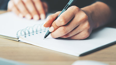 A close view of a person writing in a journal