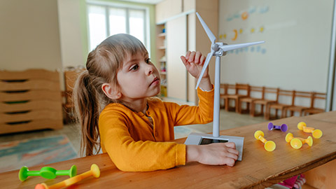 A small child examining a model wind turbine