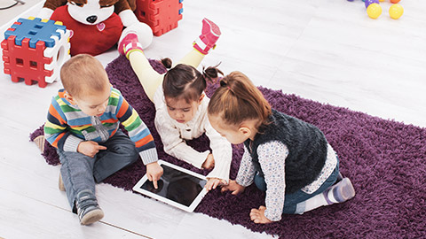 3 infants playing with a tablet device