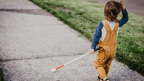 A visually-impaired child walking on a footpath