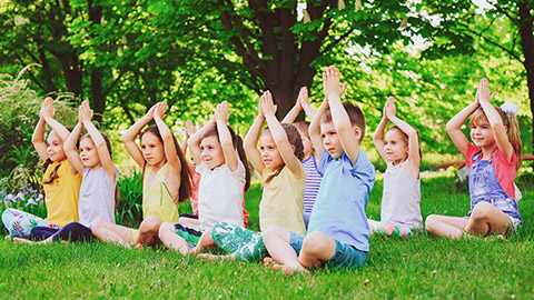 A group of kids doing some meditation exercise outside