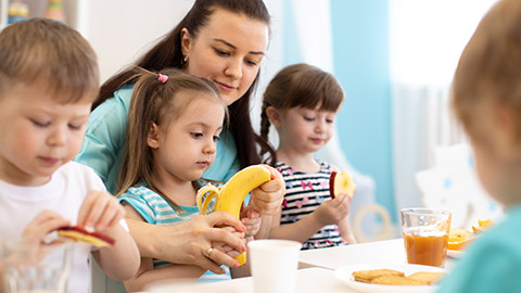 A child care worker helping a child with their food