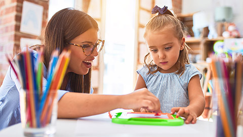 A teacher helping a young student in a kindergarten