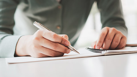 A close view of a person writing on a notebook in an office