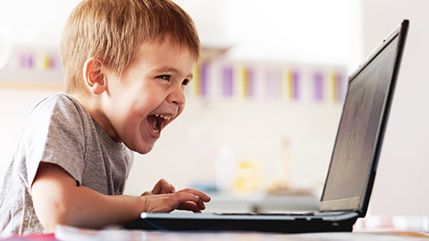 A young child playing a game on a laptop