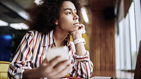 Woman thinking with phone on hand