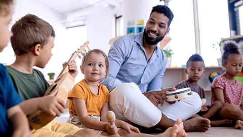 kindergarten playing instrument with adult guide