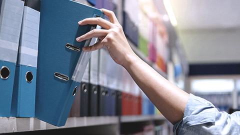 Hand choosing blue binder on shelf