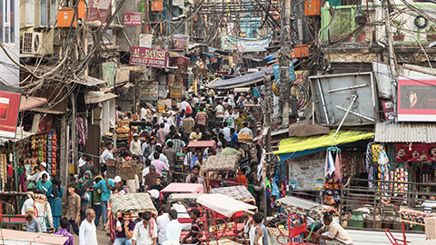 people and rickshaws move slowly in the very crowded streets