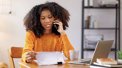 woman having business call over mobile phone and using laptop at home