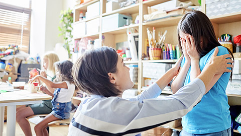 Side view of young female comforting crying girl during lesson in art school