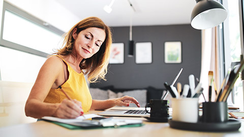 A business owner writing a report on a laptop