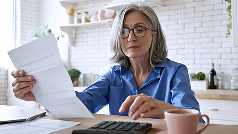 Matured woman holding paper and calculator