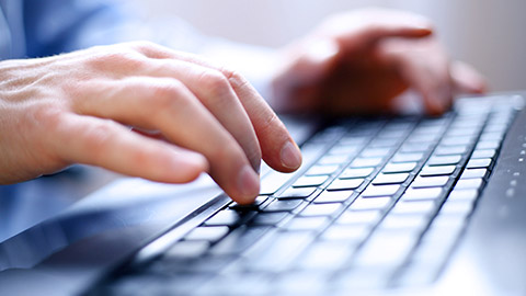 Close-up of man's hands typing on the computer