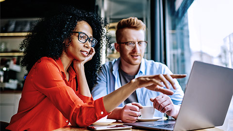 man and woman discussing over coffee and computer