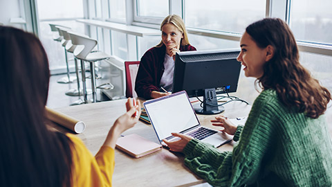 Female crew of skilled designers having conversation during brainstorming session in office