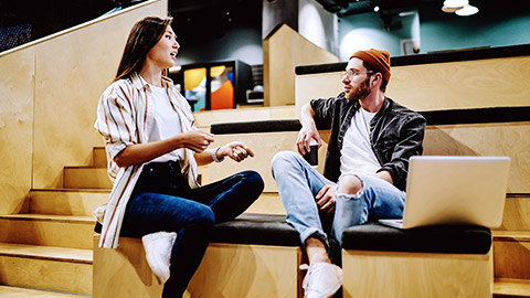 Man and woman talking on stairs with computer