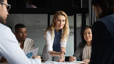 Confident skilled businesswoman explain marketing data paper report financial results analysis to multi-ethnic colleagues