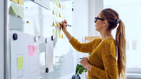 woman working in startup office writing on whiteboard