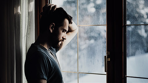 An upset person leaning by the glass door